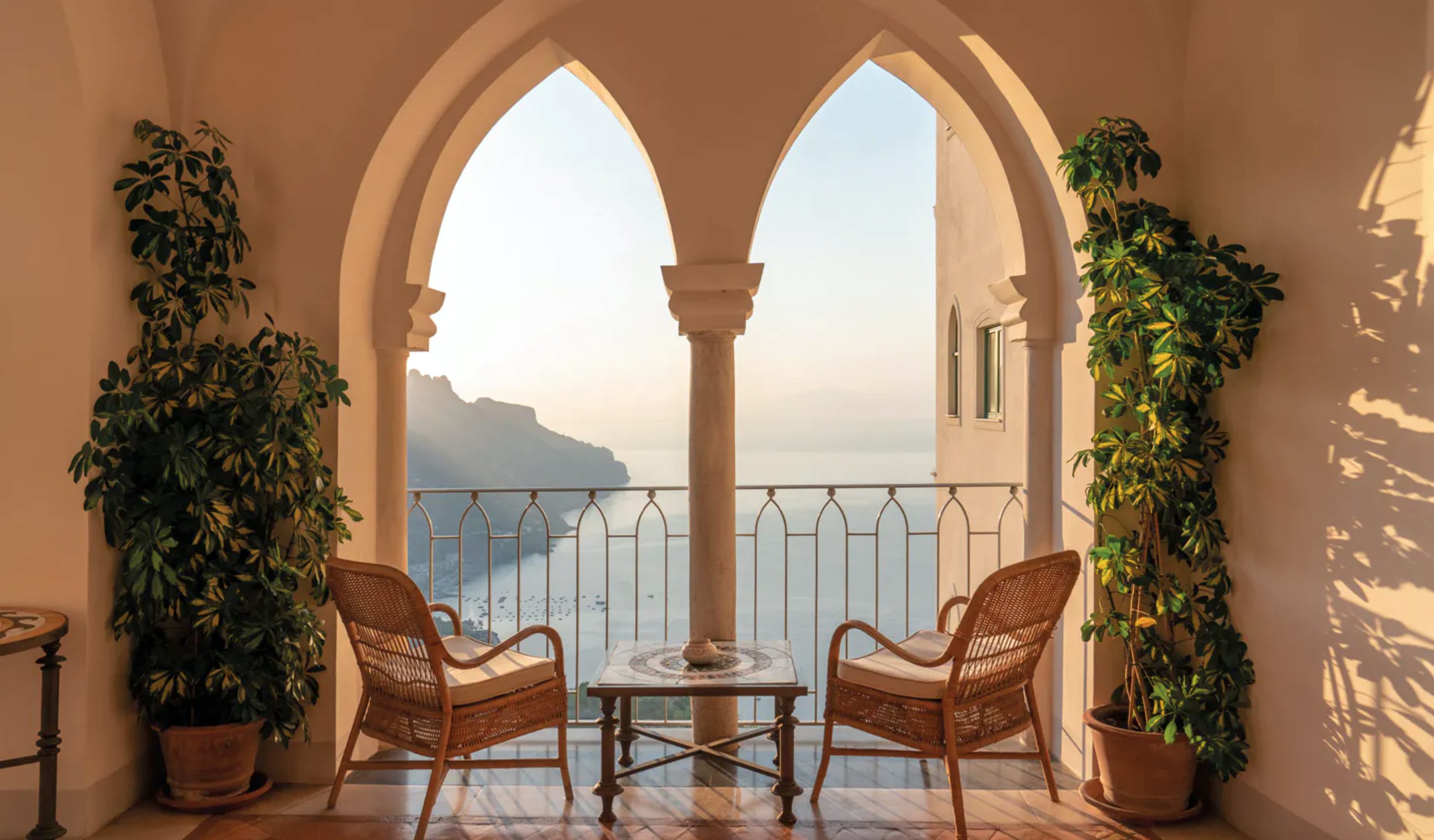 Two wicker chairs on a balcony overlooking the sea