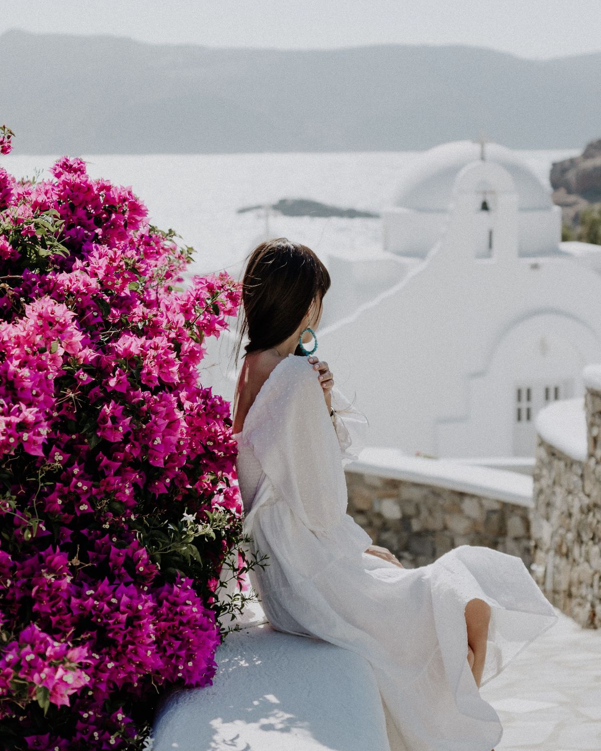 Woman beside bougainvillea overlooking the sea